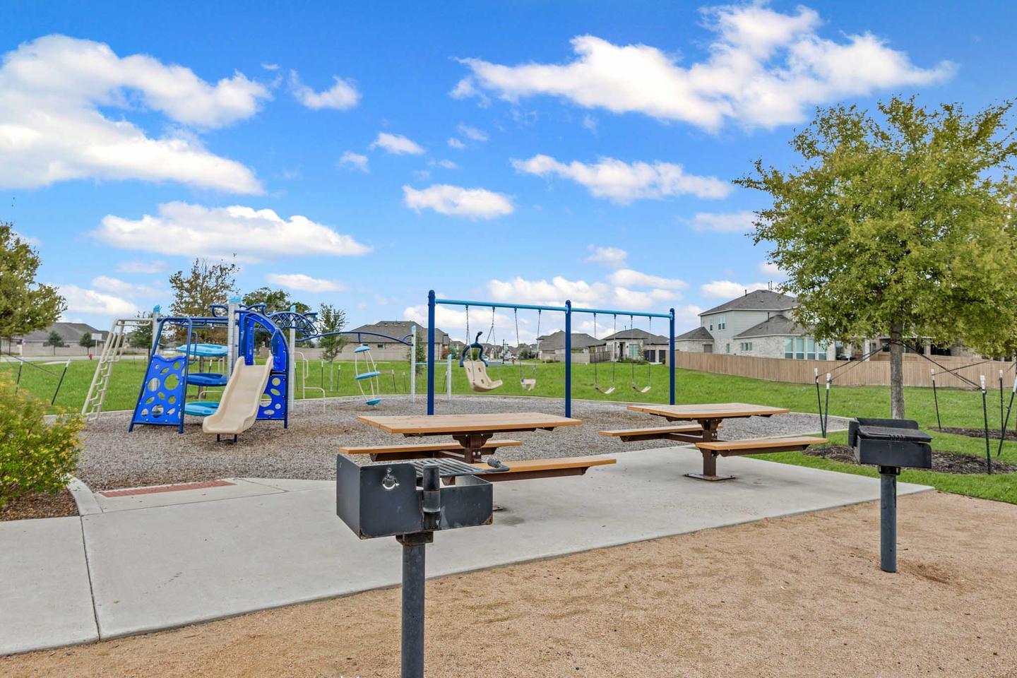 Community playground and grill stations in South Austin with picnic tables under open sky