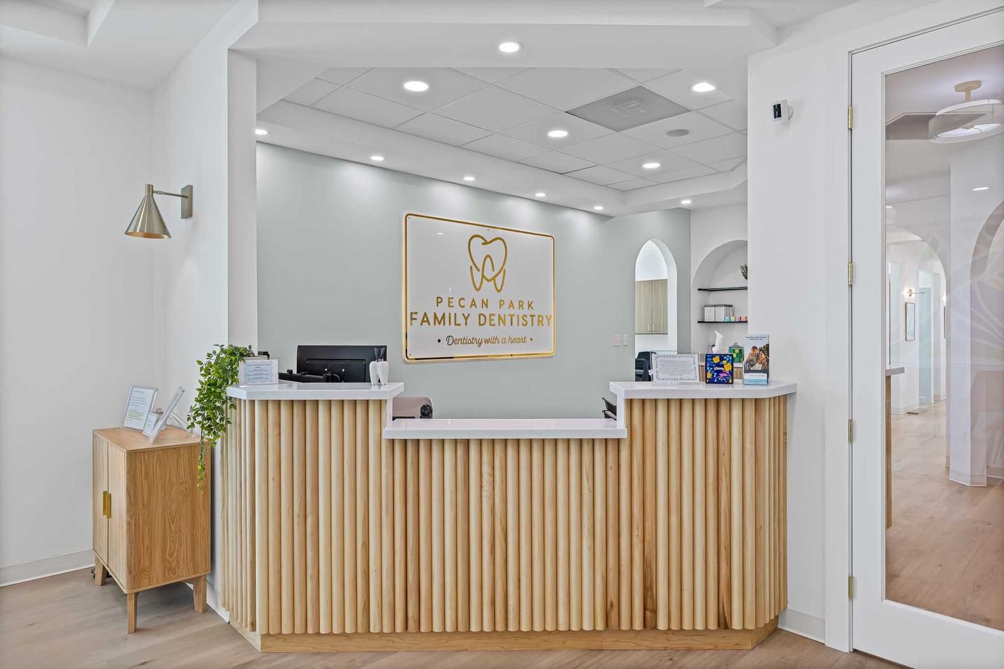 Dental practice reception desk in Cedar Park with pale timber paneling and pendant lights