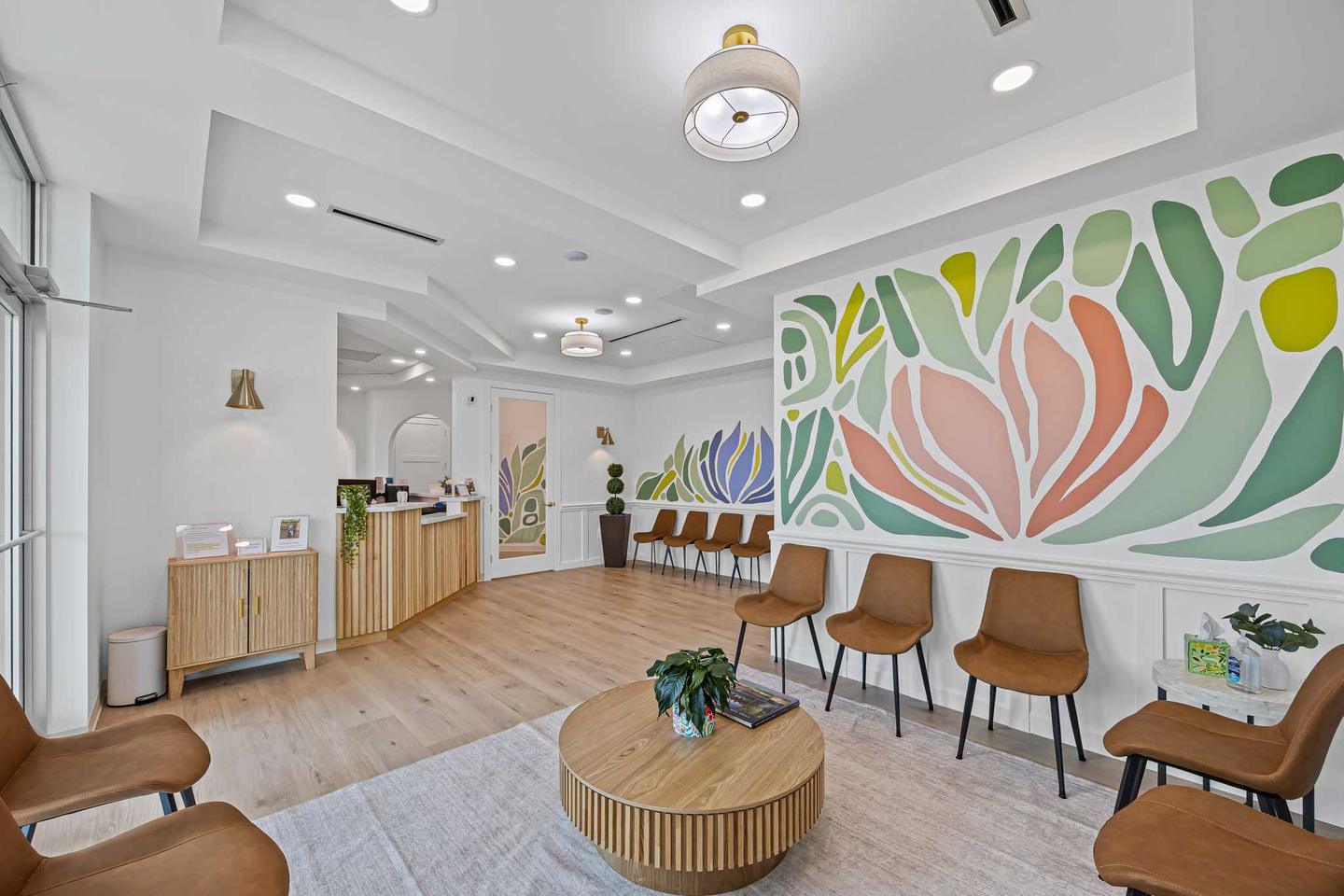 Waiting room in North Austin with a painted floral mural, timber chairs and a round table