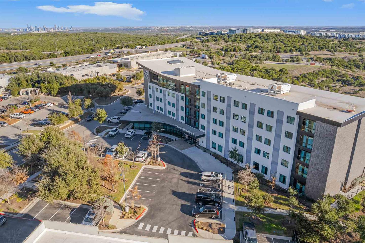 Aerial view of a four story apartment community with its parking court and landscaping