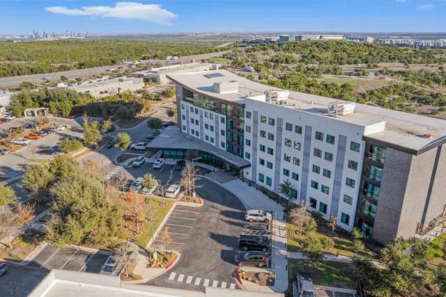 Aerial view of a four story apartment community with its parking court and landscaping