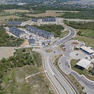 Aerial view of a Hutto apartment community with a pool and central amenity building