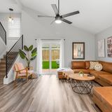 Two story condo living room with an open stair, a tan sectional and patio doors to a private yard