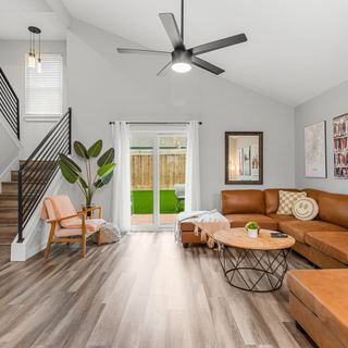Two story condo living room with an open stair, a tan sectional and patio doors to a private yard