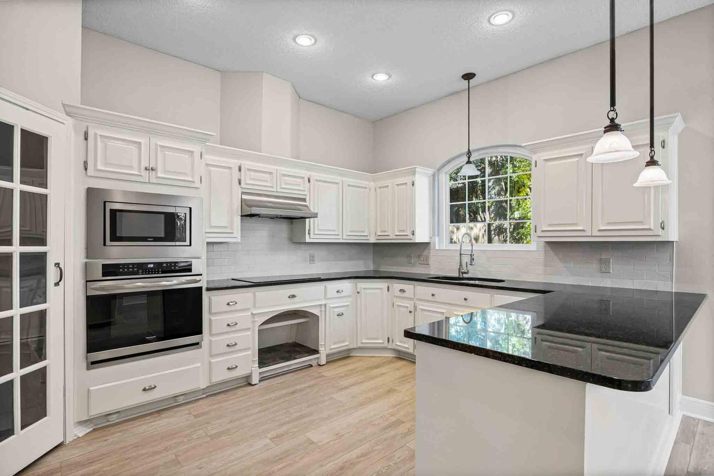 Luxury kitchen with an arched pantry opening, a long island and a dark stone countertop