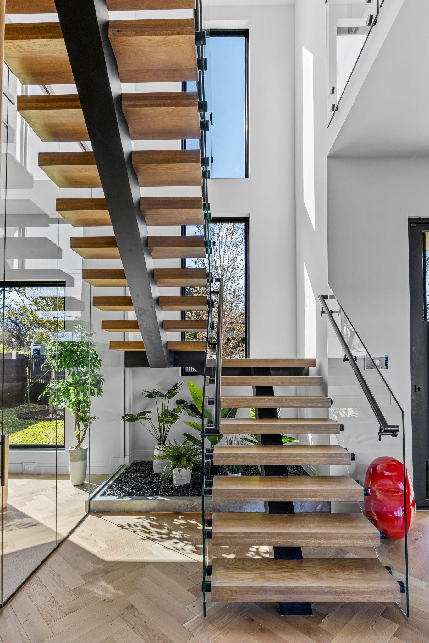 Double height stair core wrapped in glass, looking through to a planted courtyard