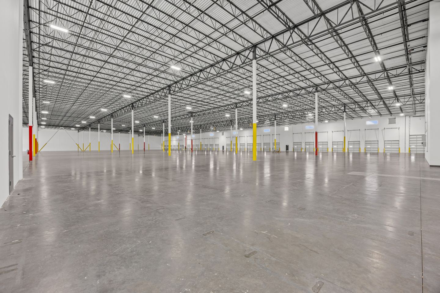 Clear span warehouse interior with rows of LED high bays and a long line of dock doors