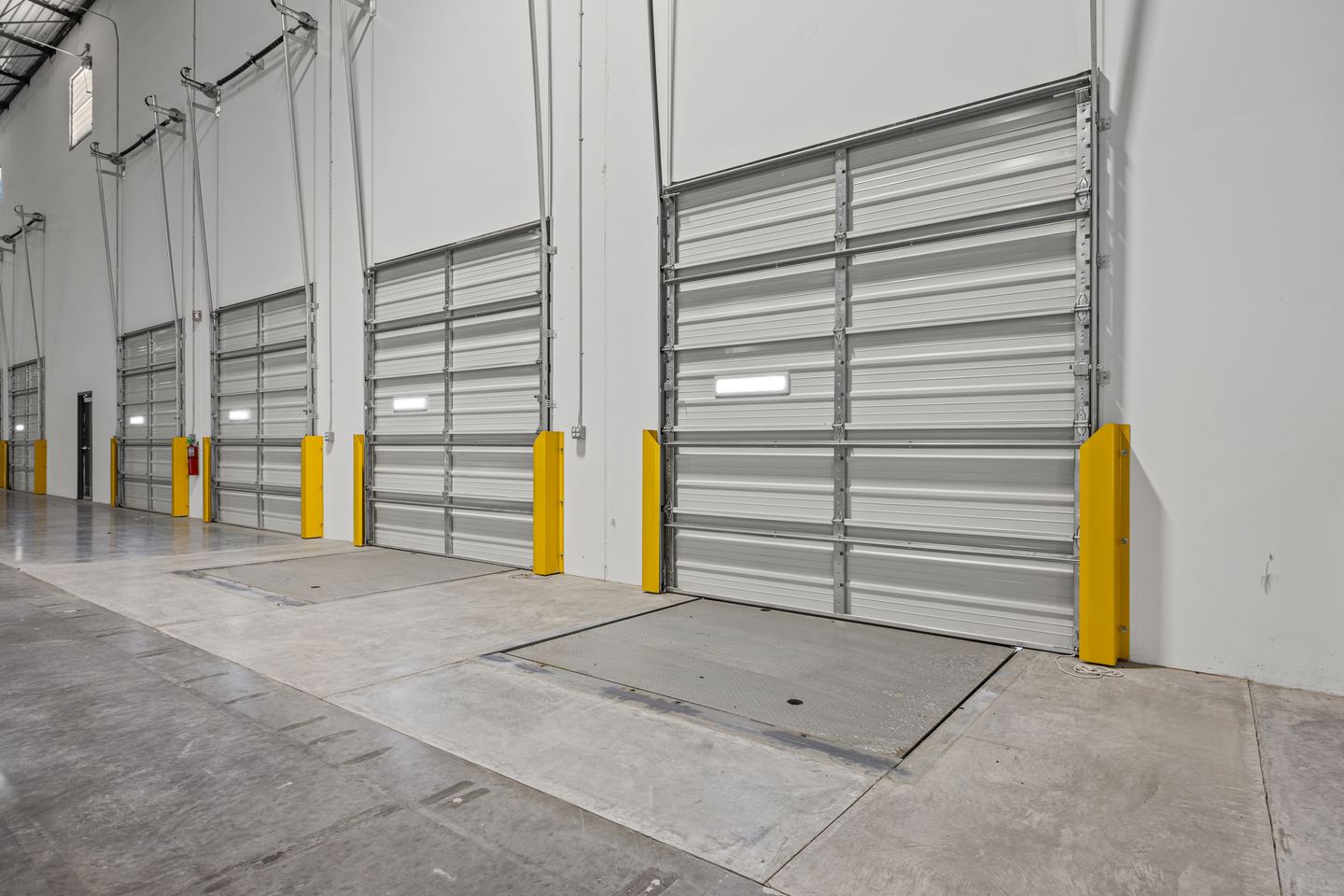 Dock doors with pit levelers set into the slab, shot low along the wall