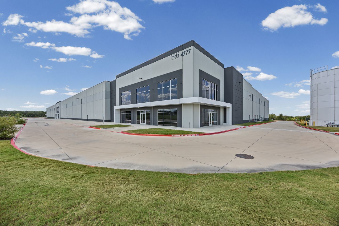 New tilt wall industrial building with a two story glazed office front and a curving concrete drive