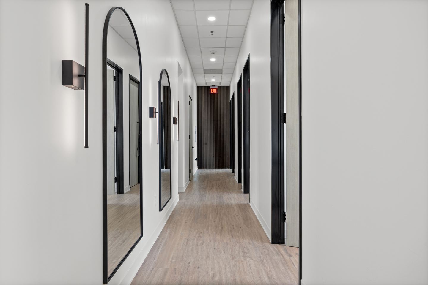 Clinic corridor with arched black framed mirrors and matte black door frames