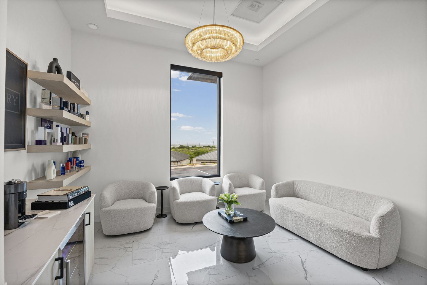 Patient lounge with boucle armchairs and sofa, a crystal chandelier and product shelving