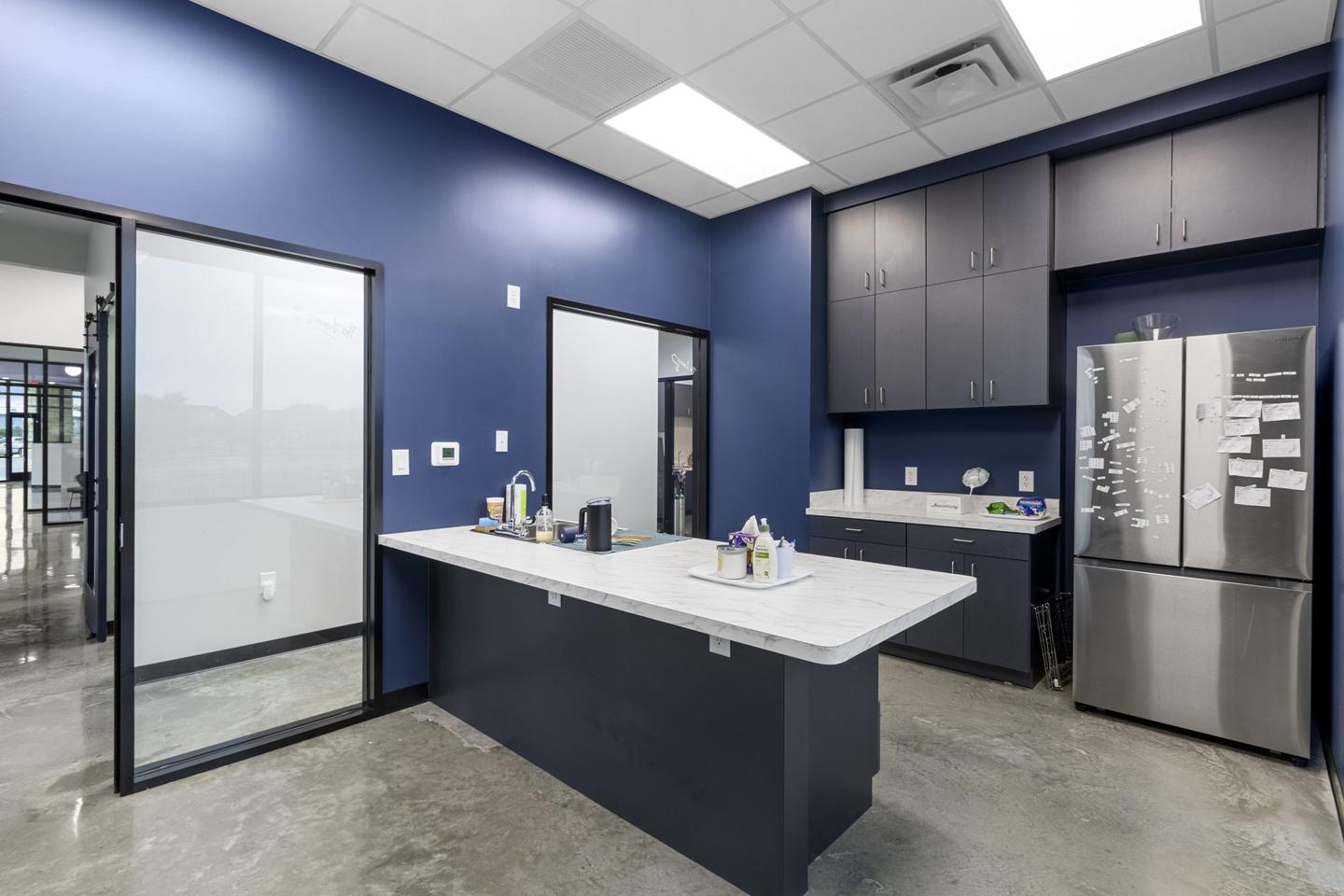 Consult room with a navy accent wall, an island worktop and a stainless refrigerator