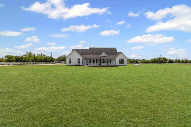 Ranch house set back on open acreage outside Lockhart with fenced pasture to the tree line