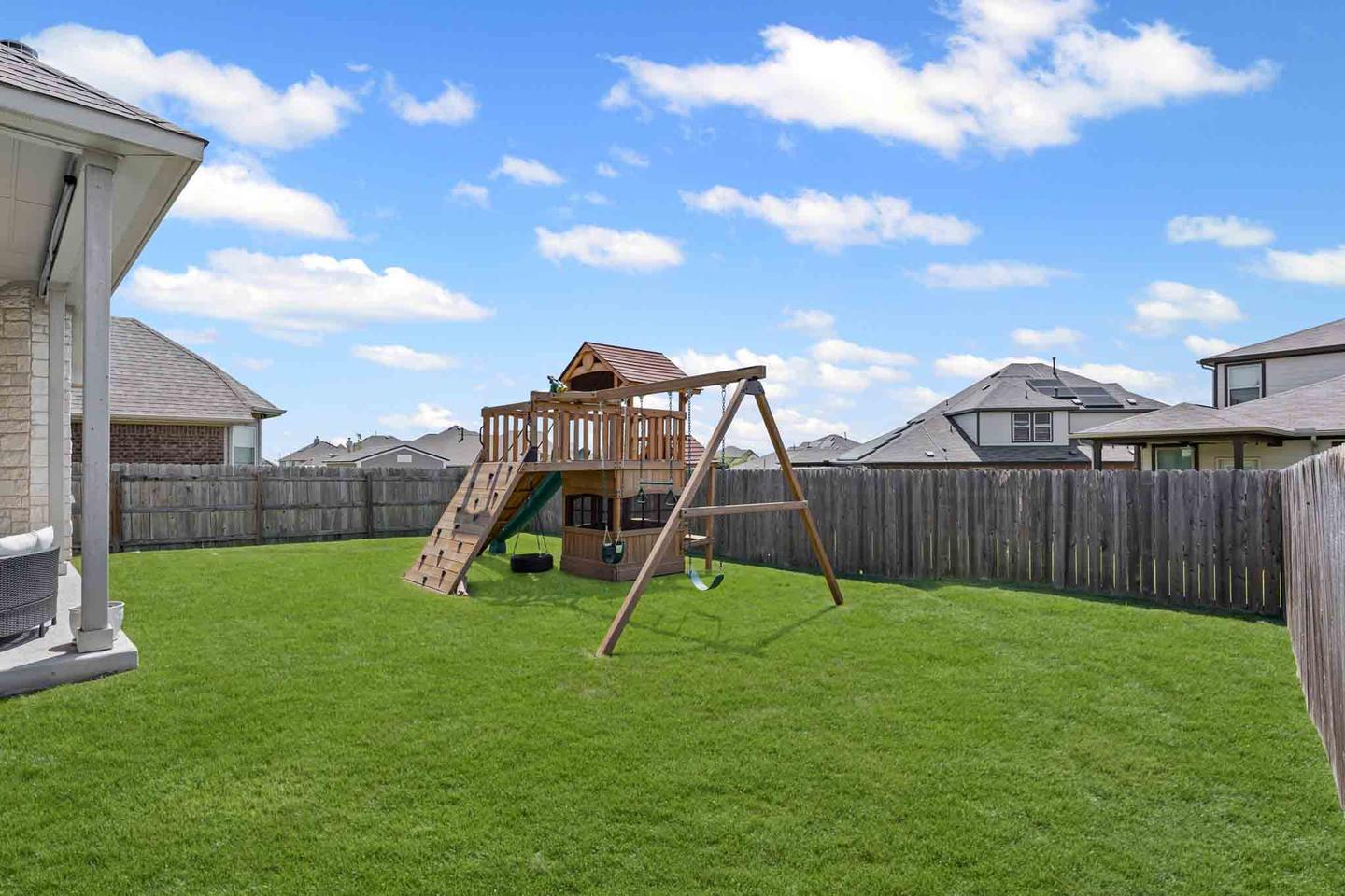 Fenced backyard in Leander with a swing set and a level lawn