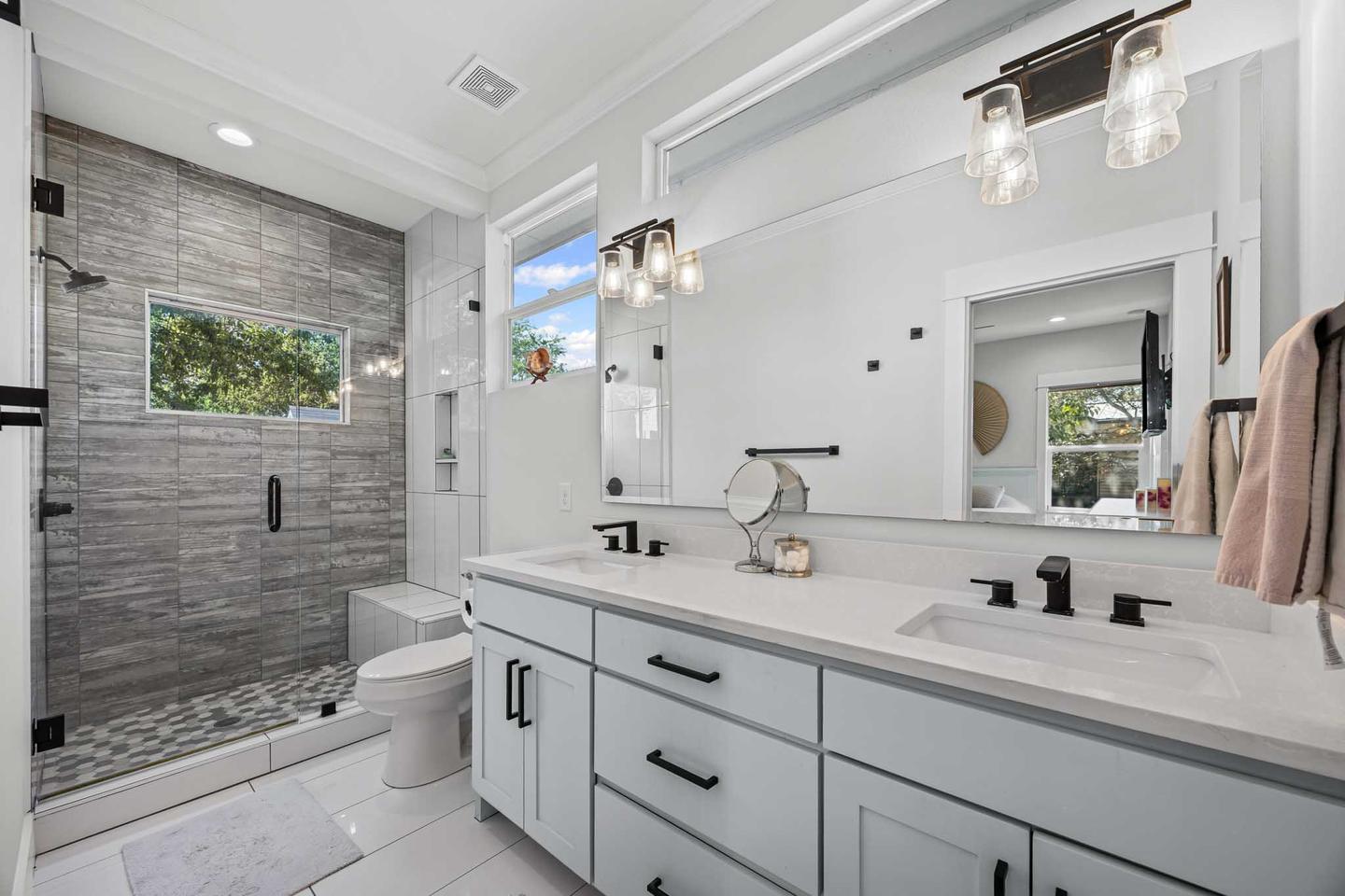 Bathroom in North Austin with a stone tiled wall, a double vanity and framed mirrors