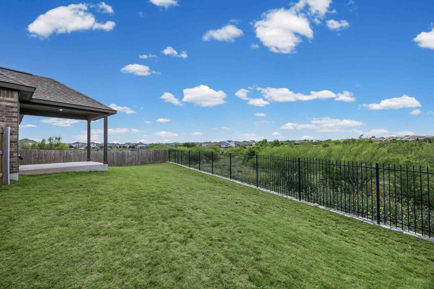 Covered patio and lawn at the back of an Austin home, photographed in clear afternoon light