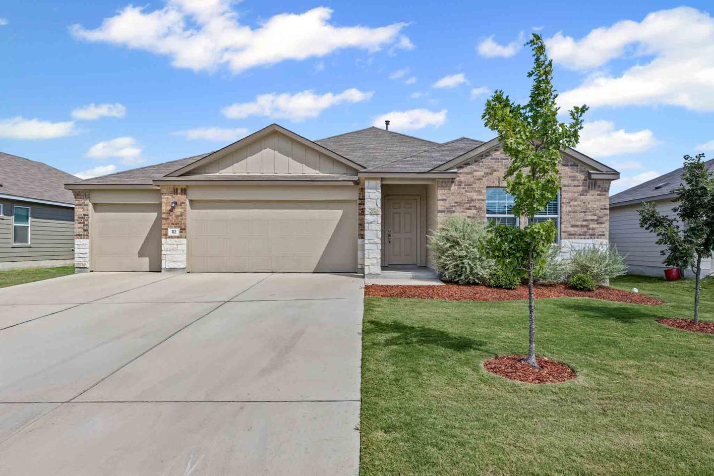 Gray single story home in Kyle photographed from the street with a mown front lawn