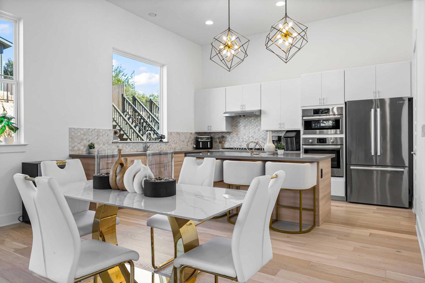 Westlake kitchen open to a dining area with white chairs and a run of windows