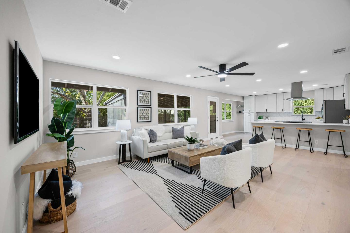 Living room in a Buda home opening onto the kitchen, with a ceiling fan and light flooring