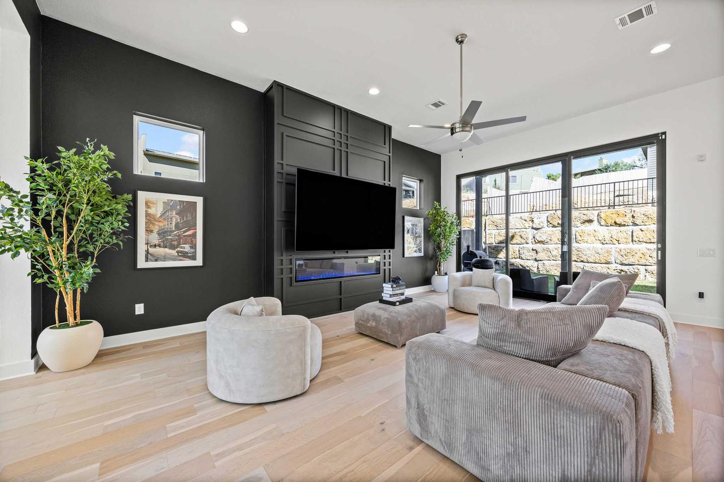 Living room with a dark accent wall, a wall mounted television and a view to the yard