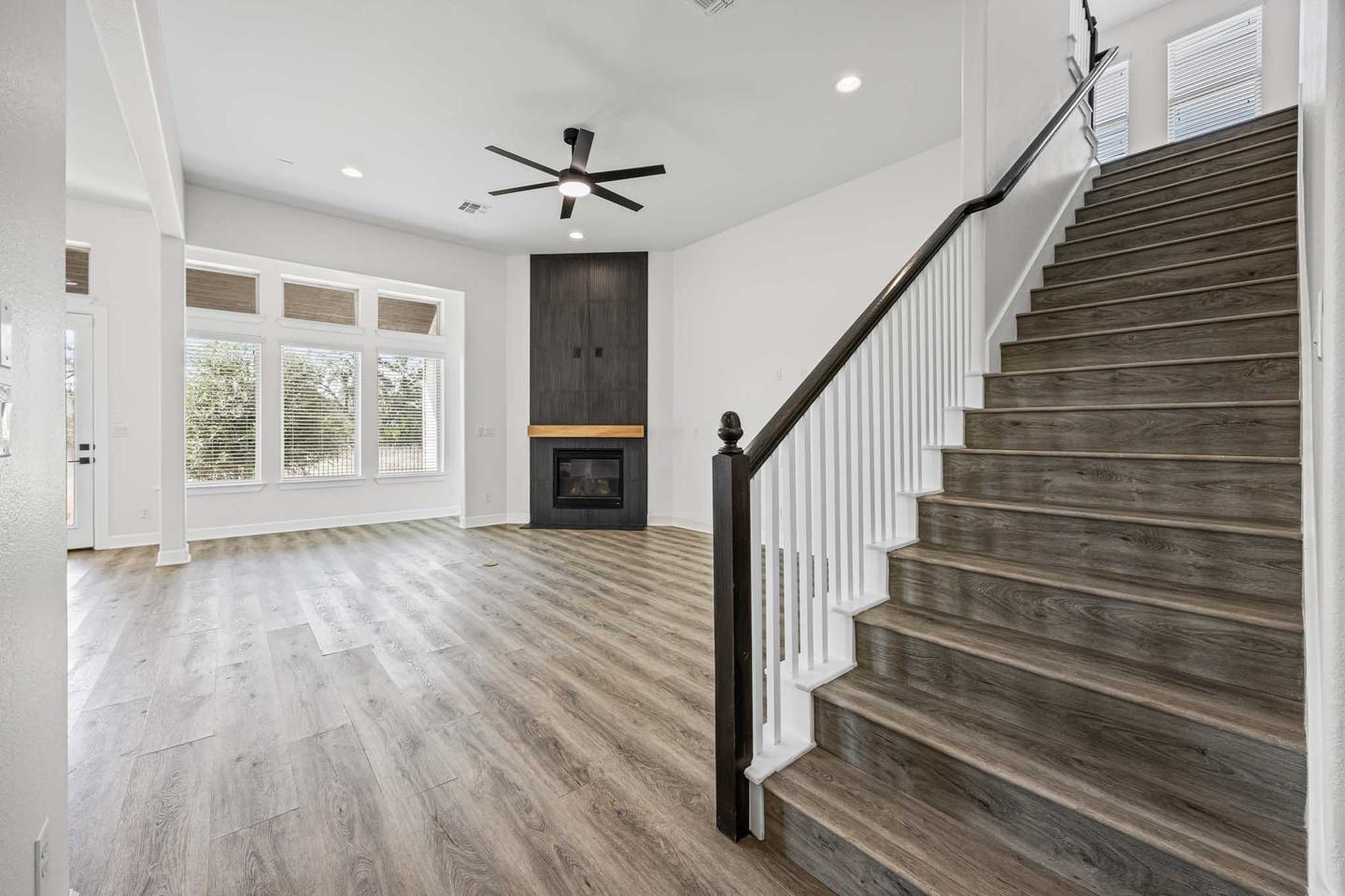 Staircase and landing in a Dripping Springs home with a dark handrail and light walls