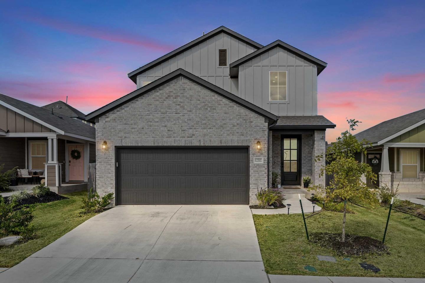 Buda home photographed at dusk with warm interior light and a deep blue sky behind the roofline