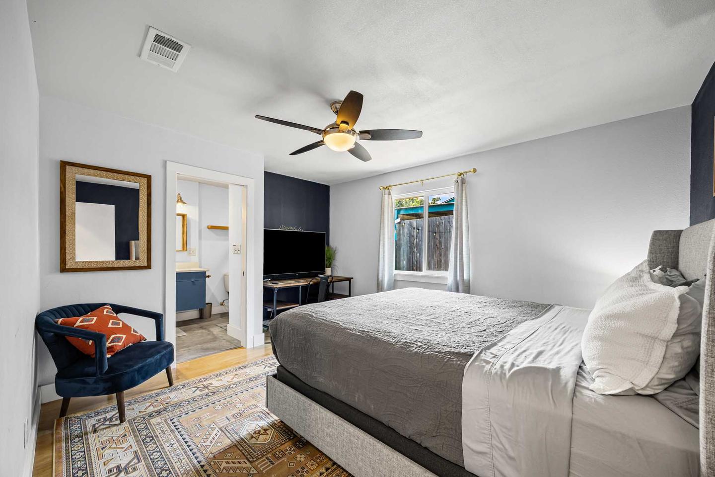 Short term rental bedroom in East Austin with a made bed, bedside lamps and a framed print above the headboard