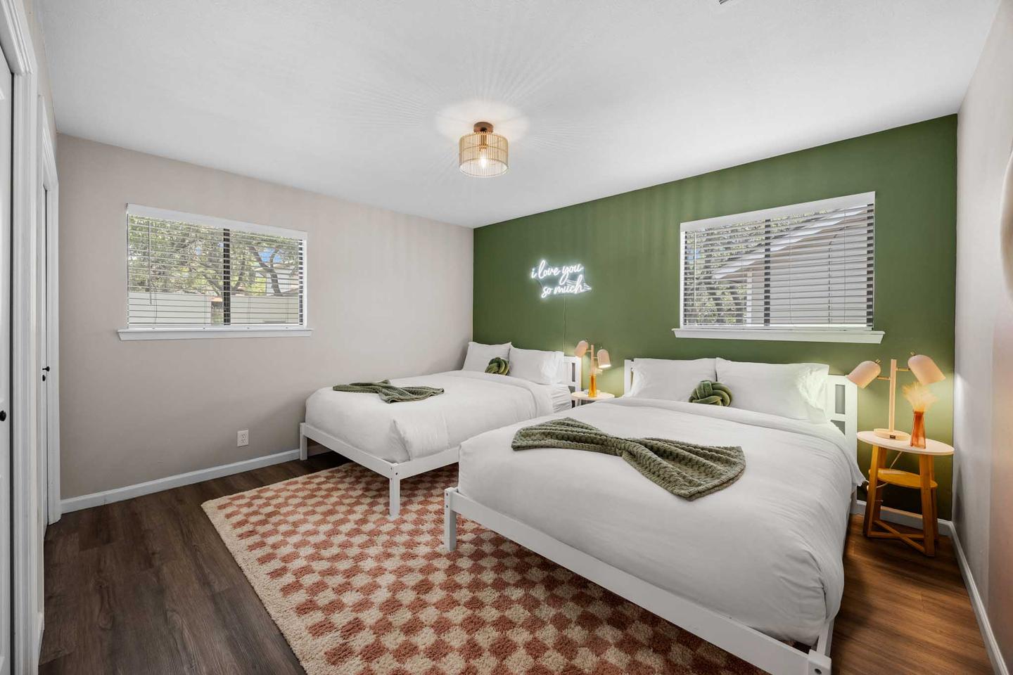 Short term rental bedroom in Westlake with a green accent wall and a patterned rug