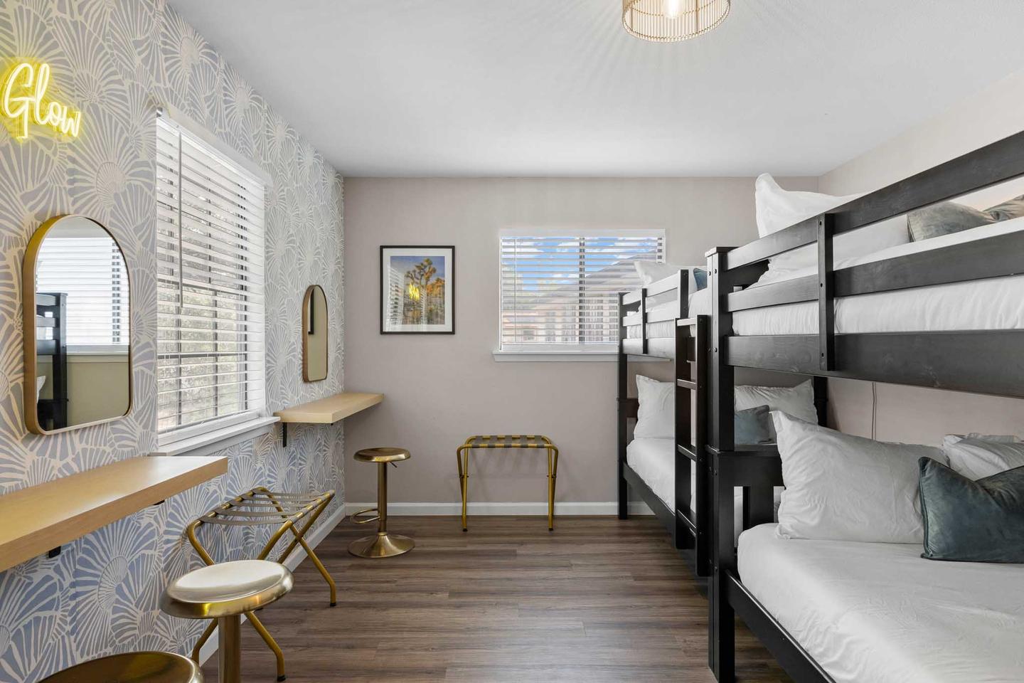 Short term rental bunk room in Round Rock with a black metal bunk bed, a desk and a neon sign