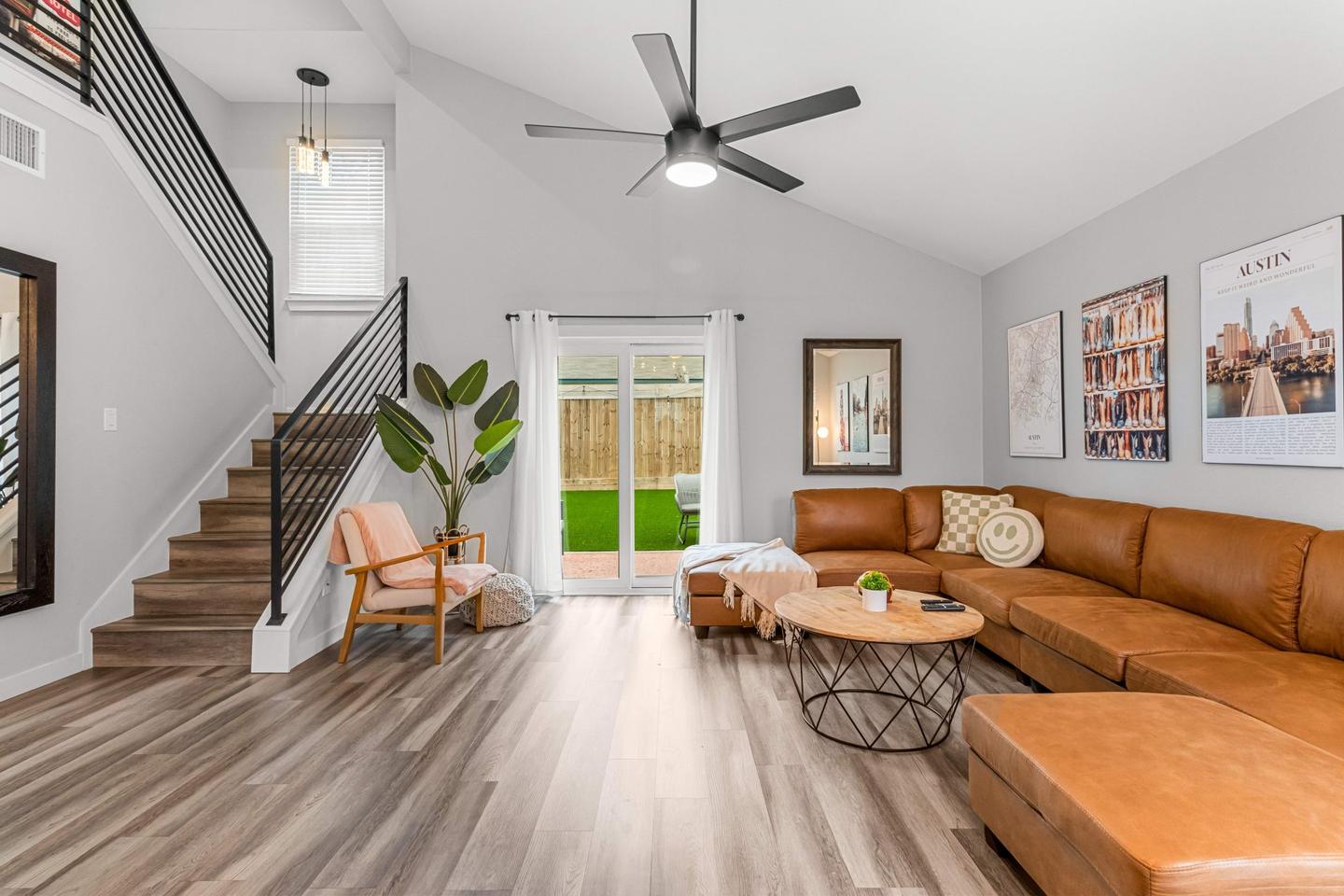 Short term rental living room in South Austin with a tan leather sectional and an open stair