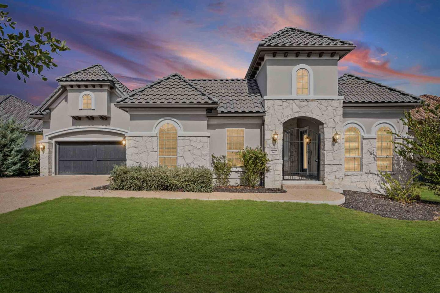 Two story home in Austin photographed at true twilight with warm light in the windows and a violet sky