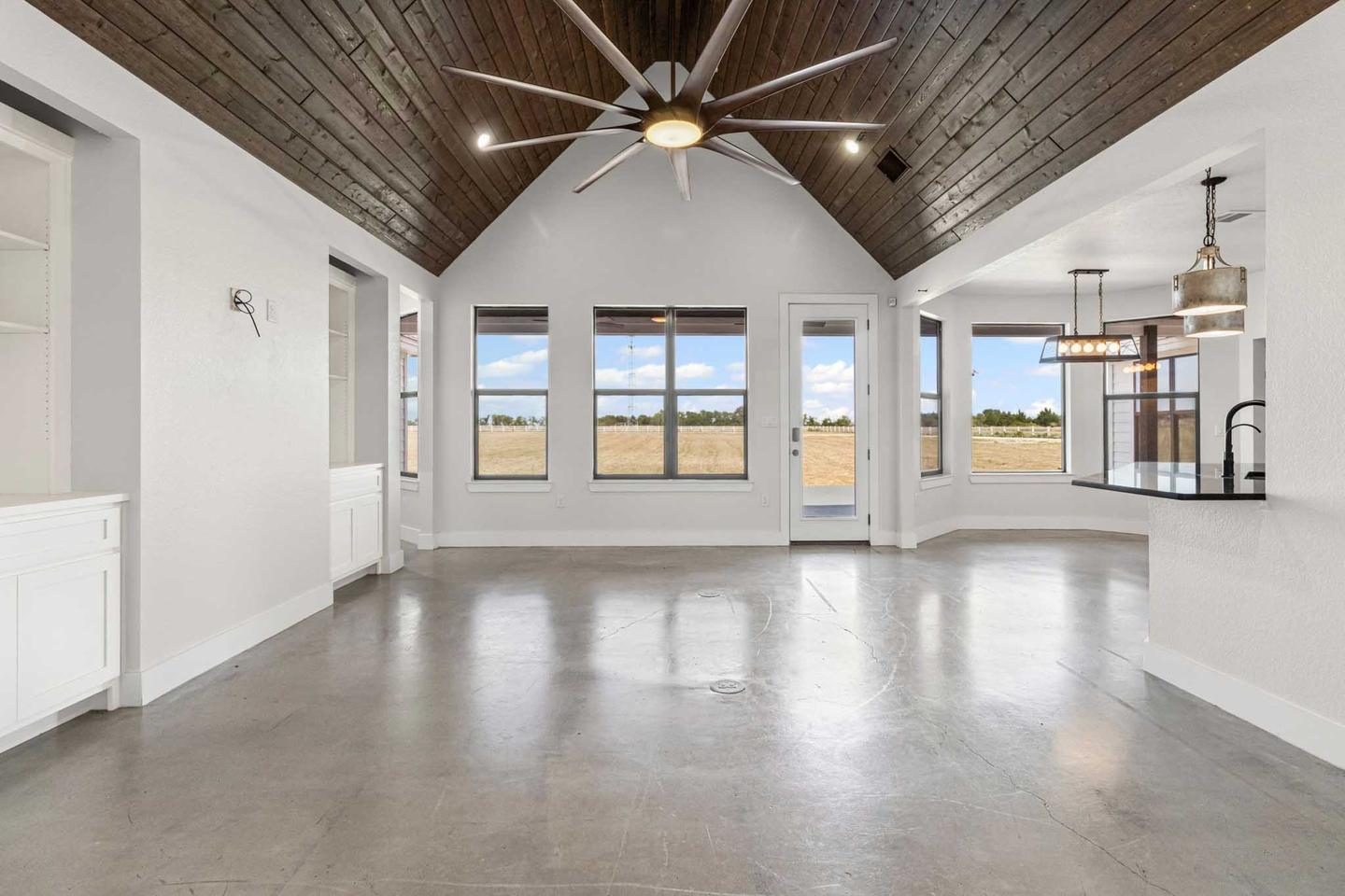 Empty great room in Cedar Park with a timber clad vaulted ceiling and bare floor