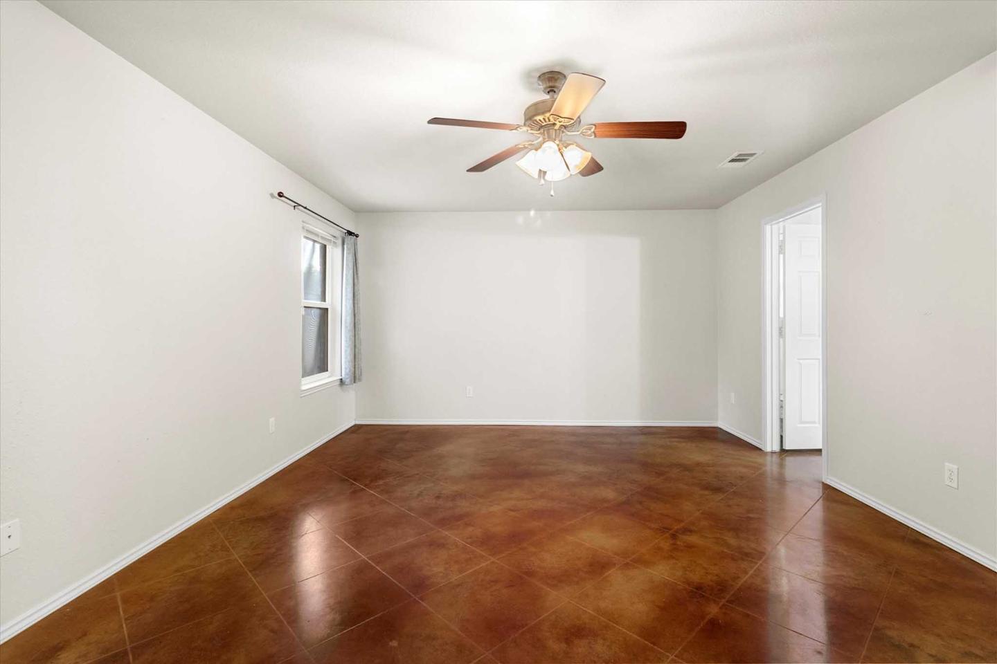 Empty bedroom in South Austin with dark wood flooring and a single window
