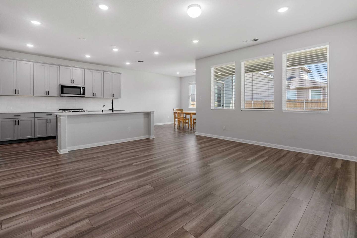 Empty open plan living room in West Austin with wood floors and a kitchen island behind it