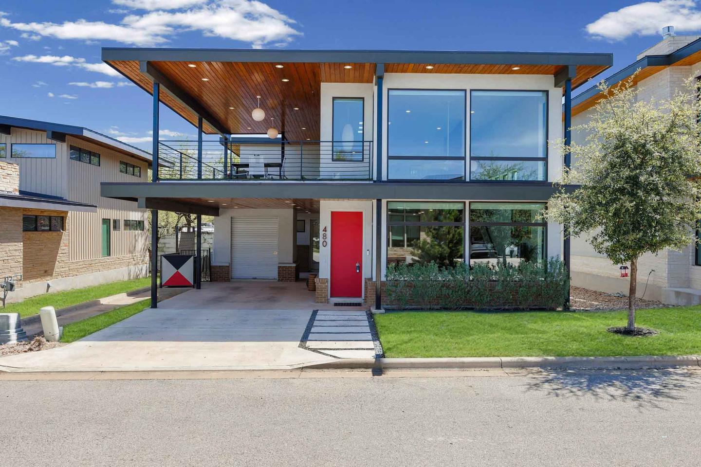 Modern two story home in North Austin with a glass frontage and a red front door, photographed in daylight