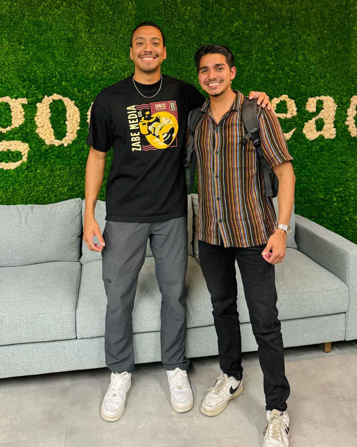Abriel and Isaiah, the two founders of ZABE Media, standing together in front of a green moss wall