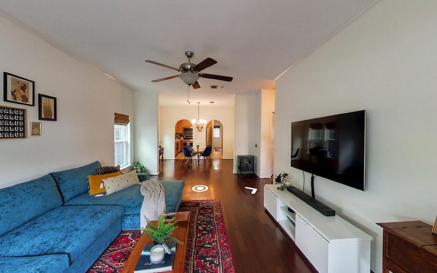Living room captured for a Zillow 3D Home interactive tour, with a blue sofa and a wall mounted television
