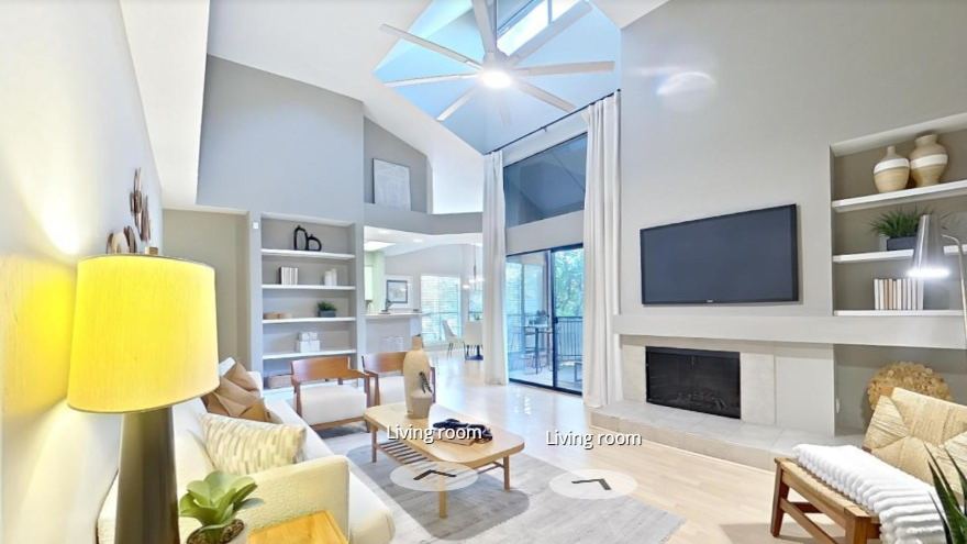 Zillow 3D Home tour view of a condo living room with a vaulted ceiling, built in shelves and a fireplace